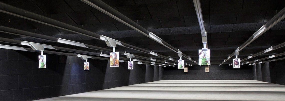 A row of guns in a gun range with pictures on them.