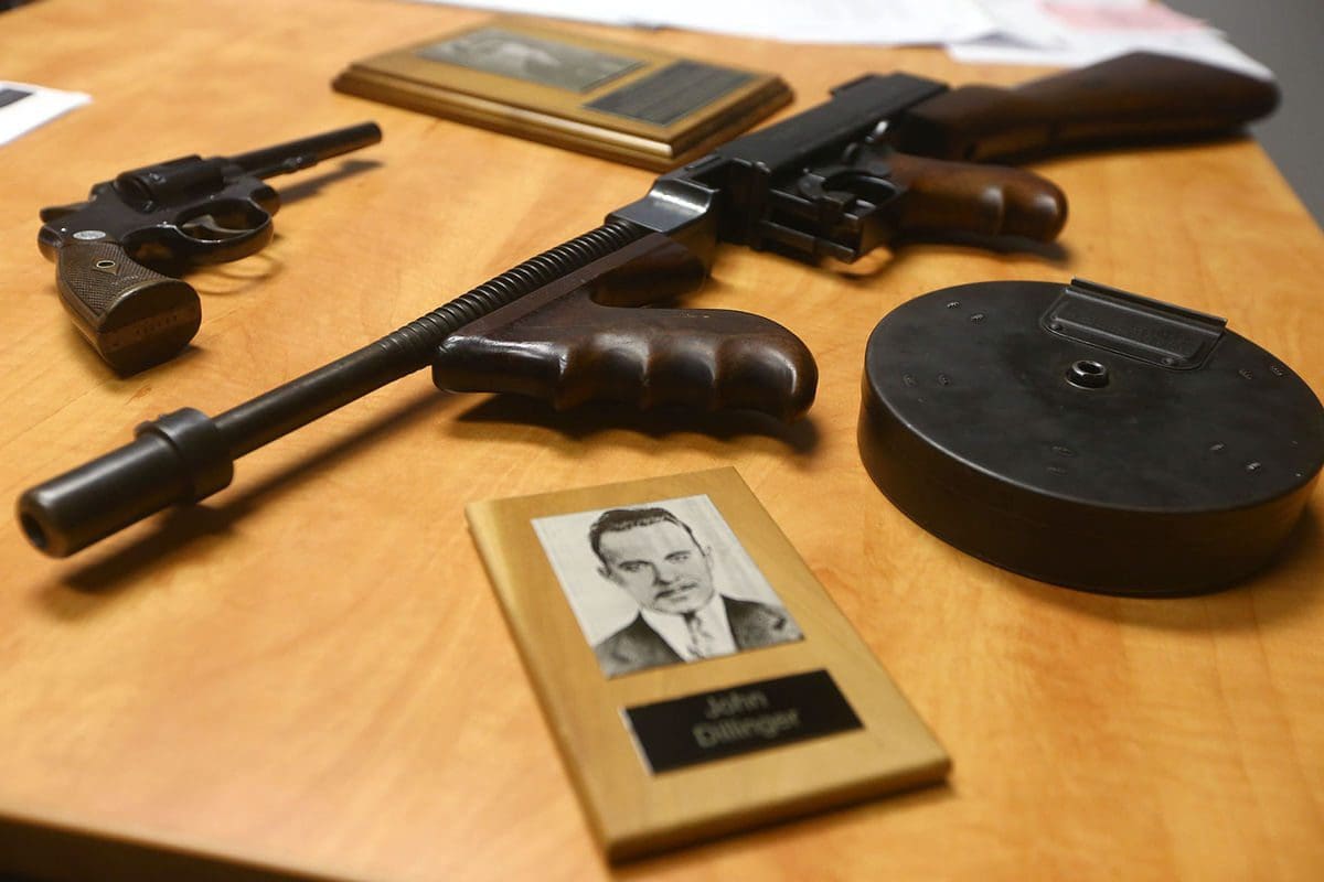 A table with guns and a picture of an old man.