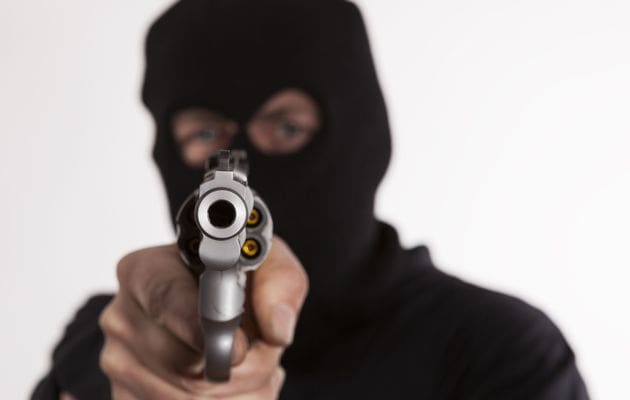 A person in black mask holding a gun.