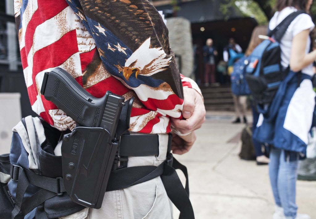 A man in american flag shirt holding a gun.