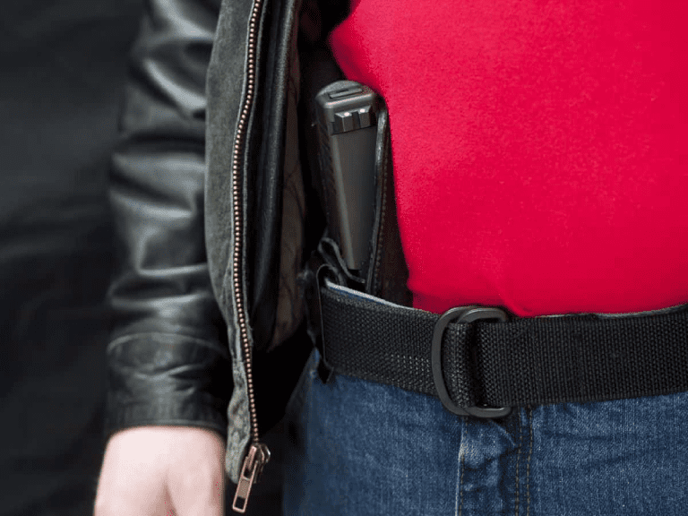 A man wearing jeans and red shirt with a holster in his belt.