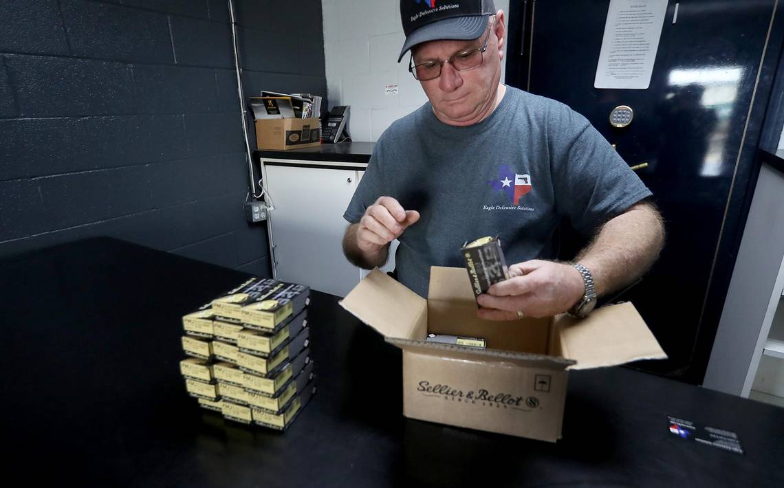 A man in grey shirt putting together boxes of cookies.