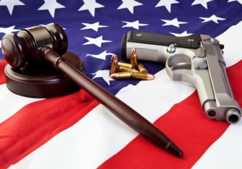 A gavel, gun and revolver on an american flag.